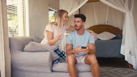 excited couple in bedroom at home celebrating positive pregnancy test result