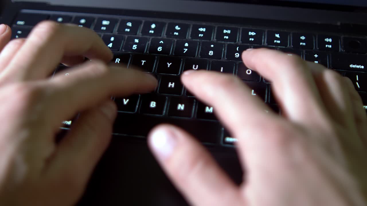Focused hands work on a laptop, highlighting the illuminated keyboard. A clean, modern workspace is subtly suggested