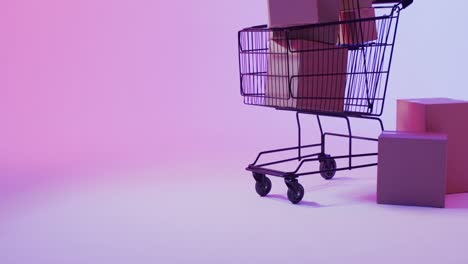 Video-of-boxes-and-shopping-trolley-with-copy-space-over-neon-purple-background