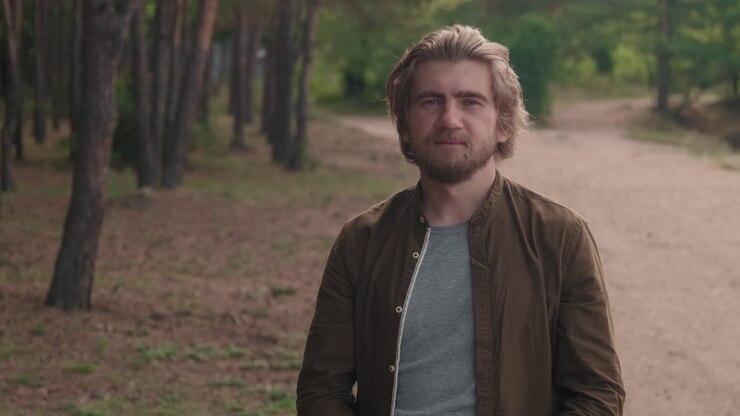 Portrait Of Man Taking Off Face Mask In Forest