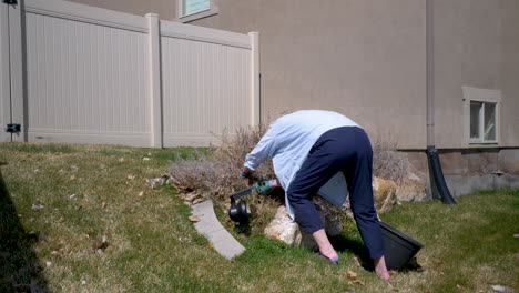 mujer madura cortando plantas muertas en el jardín para hacer espacio para el crecimiento de la primavera