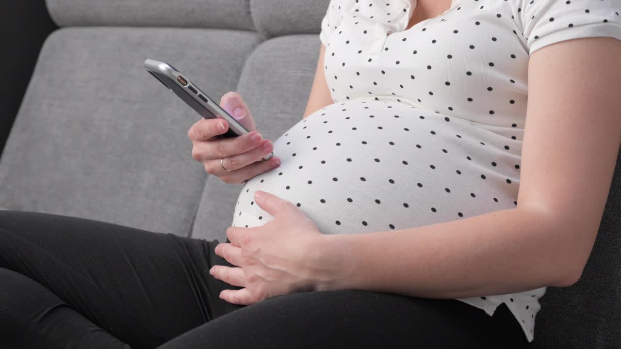Pregnant woman on sofa using phone