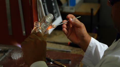 Close-up-of-male-worker-blowing-glass-in-glass-factory-4k