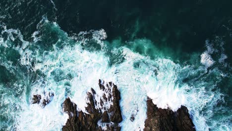 Top-Down-Shot-Over-Beautiful-Turquoise-Waters-in-Slow-Motion-with-Waves-Splashing-Over-Rocks