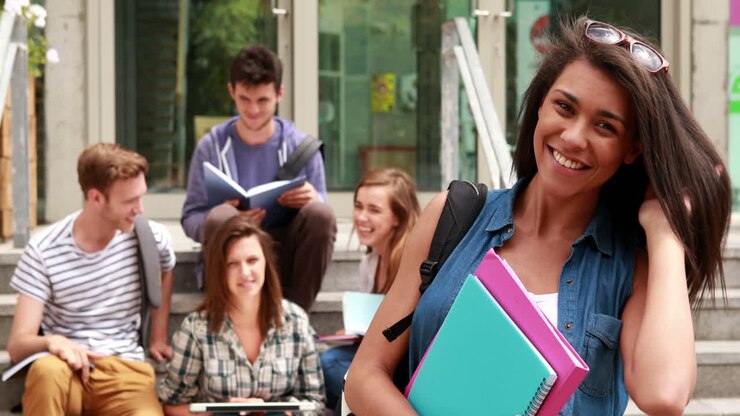 bella studentessa che posa e amici che studiano dietro di lei