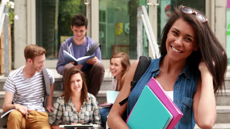 estudiante bonita posando y amigos estudiando detrás de ella