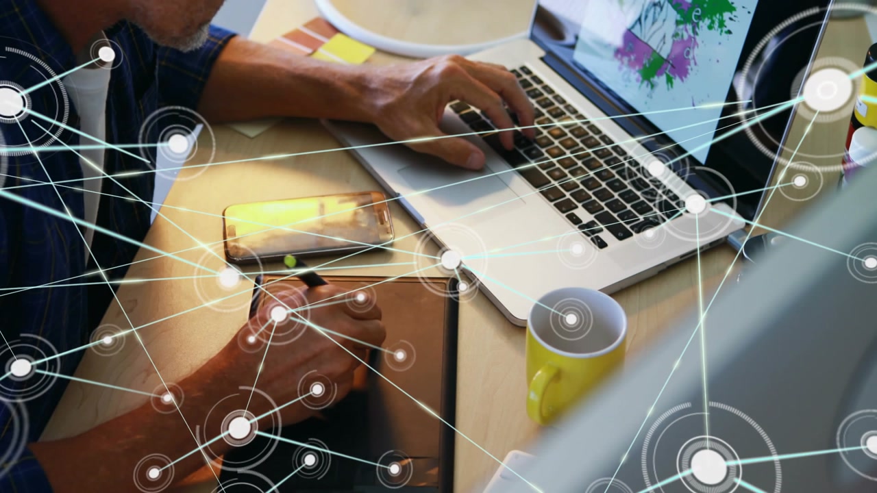 Designer holding stylus and typing, initiating network overlay from stylus to phone, mapping assets