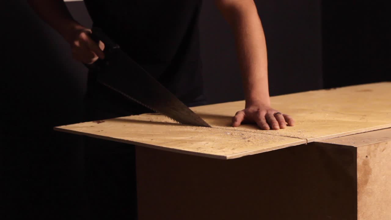 Anonymous person sawing plywood in a workshop