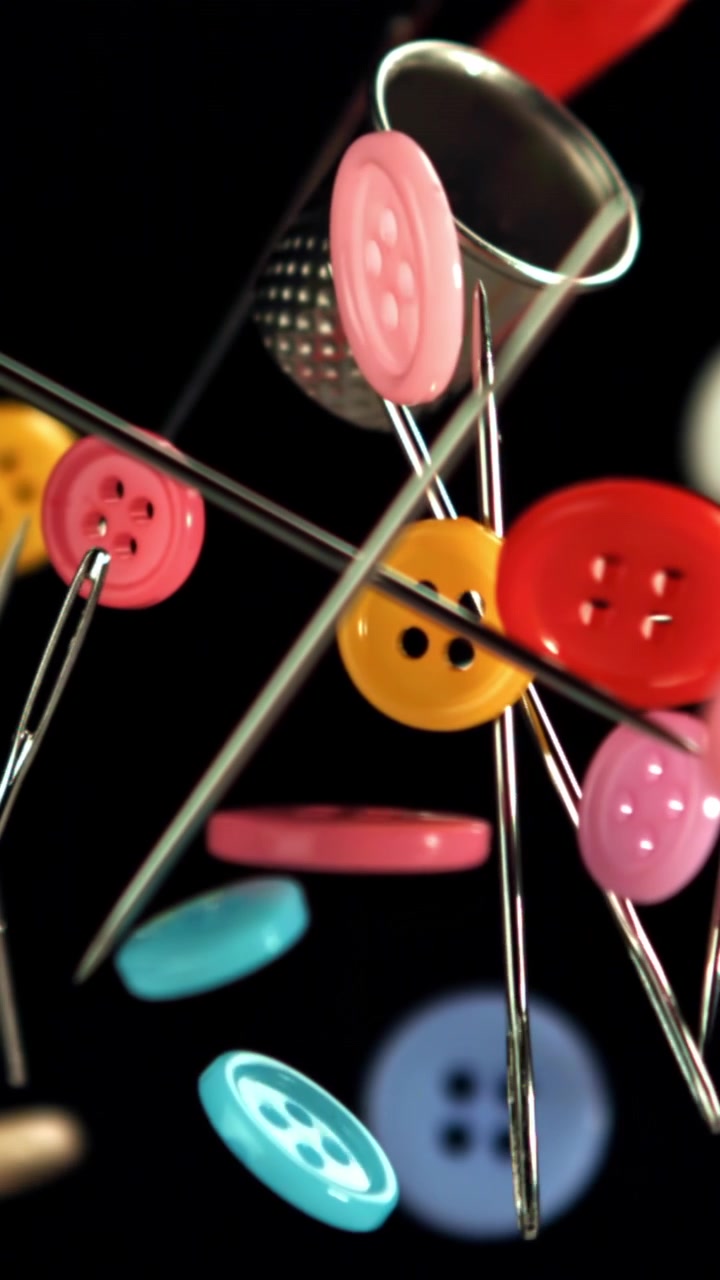 Colorful Sewing Buttons, Needles, and Thimble Against Black Background