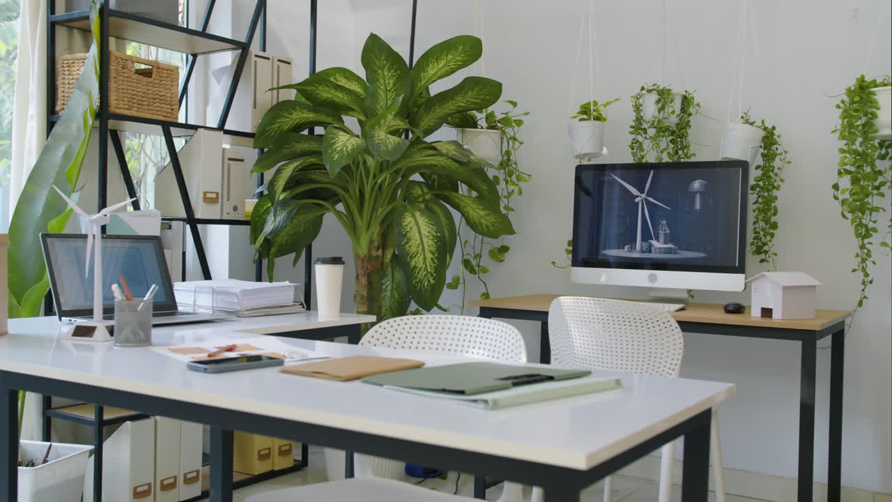 Interior de escritório verde com dispositivos digitais, mesas de trabalho e equipamentos