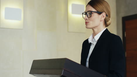 close-up view of caucasian businesswoman speaker on a podium wearing eyeglasses and formal clothes and talking in a conference room