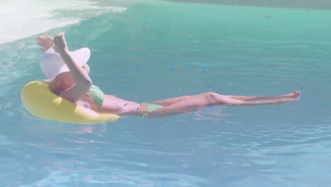 relaxing on yellow float in pool, woman wearing hat and sunglasses