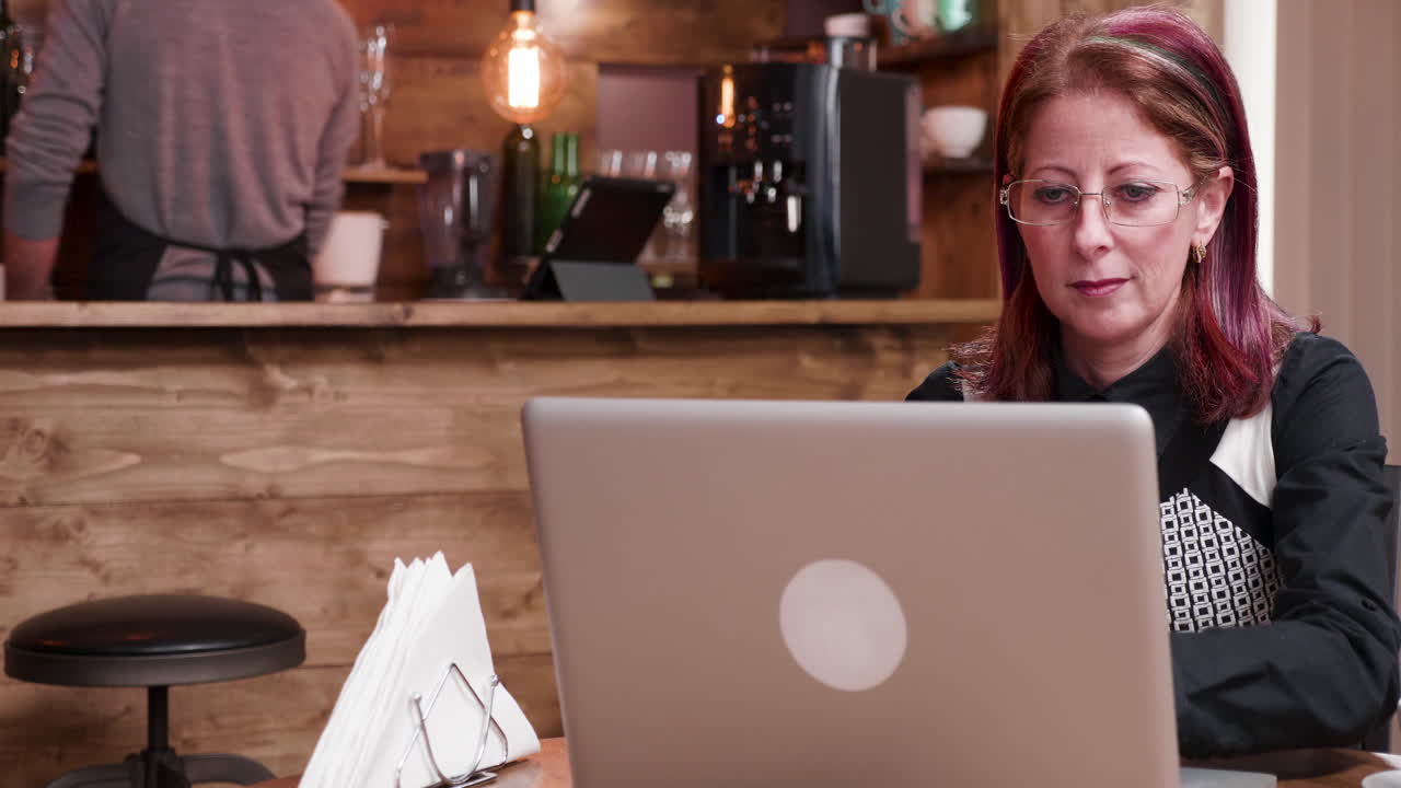 Kvinde, der arbejder på bærbar computer på café