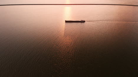 Barco-En-Silueta-Sobre-El-Mar-En-Calma-En-Lelystad,-Flevoland,-Países-Bajos-En-Una-Gloriosa-Puesta-De-Sol---Drone-Aéreo