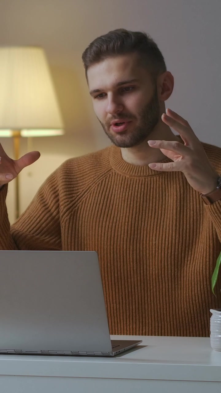 Young Man Talking and Gesturing During Video Call on Laptop