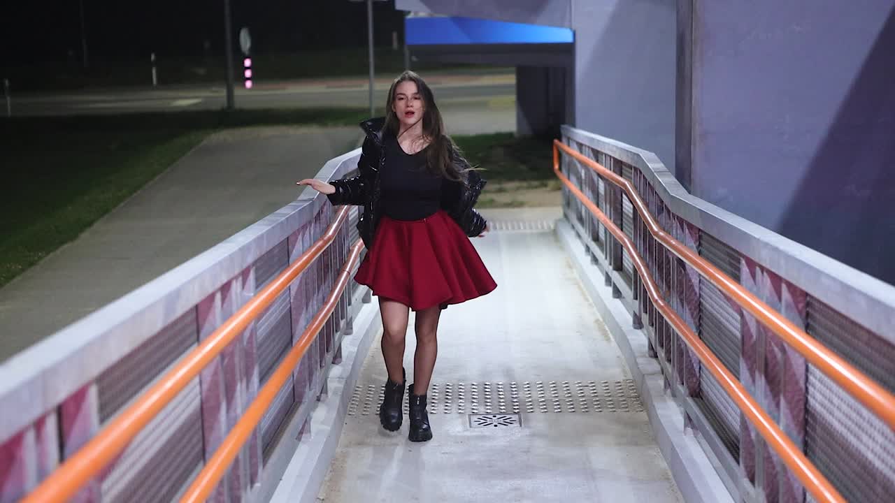 Young woman dancing and moving alone at night in urban area