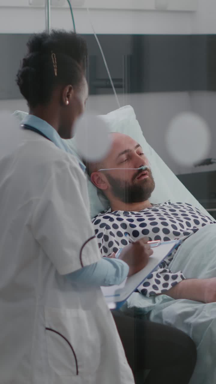 Video verticale: medico afroamericano che controlla un uomo malato monitorando i sintomi della malattia