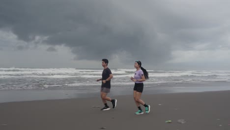 couple running on beach during cloudy day