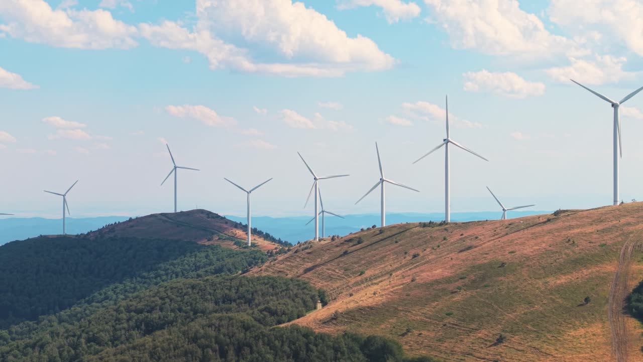 Scenic drone view of turbines spinning in high-altitude terrain with dramatic cloud movement above. Clean power meets Balkan landscape beauty
