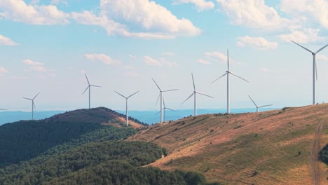 scenic drone view of turbines spinning in high-altitude terrain with dramatic cloud movement above. clean power meets balkan landscape beauty