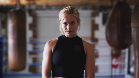 portrait of female boxer in gym training with old fashioned punching bags