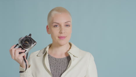 female caucasian model posing with vintage slr against blue backdrop 02