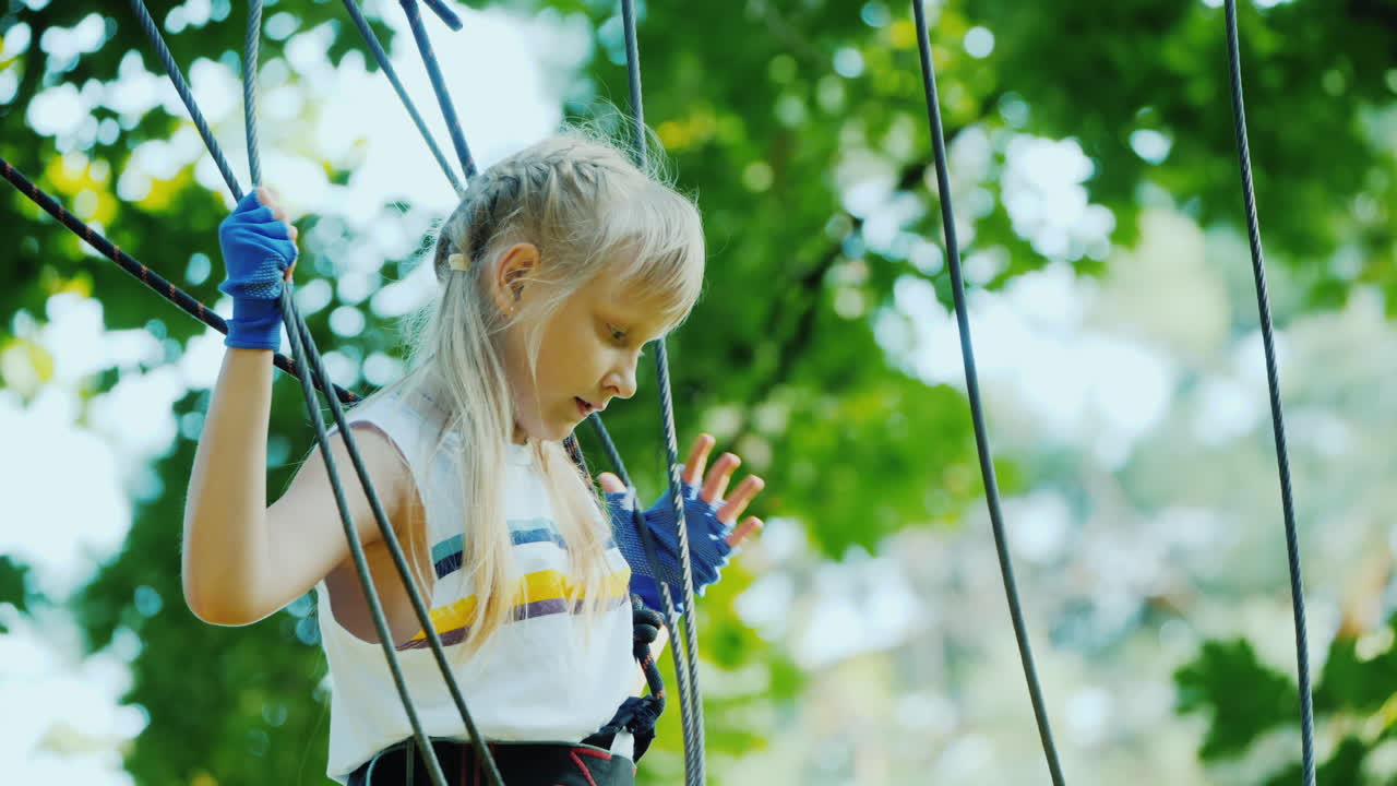 смелый ребенок идет по натянутому канату между высокими деревьями активное детство и веселье