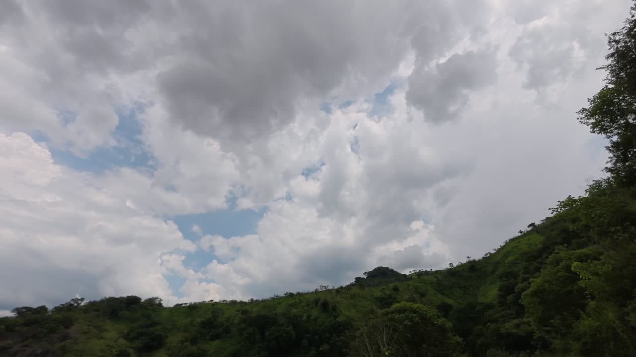 Timelapse of cloud movement above forested hills near lake in Jalisco, Mexico. Static view