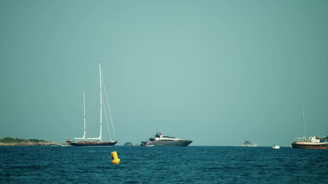 Varie imbarcazioni, inclusi un grande yacht e una barca a vela, che navigano sull'oceano blu sotto un cielo sereno. Concetto di svago e viaggio