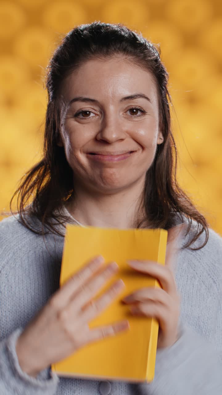Donna felice che tiene in mano un libro giallo e fa il gesto del pollice in su