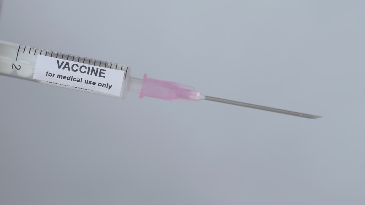 jeringa con vacuna para inmunización volteada por un dedo con guante, cierre