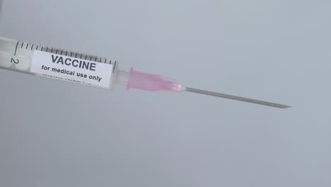 syringe with vaccine for immunization flip by a finger with glove, close up