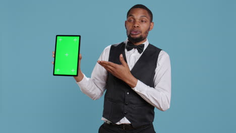 bellman hotelier showing a tablet with green screen display in studio