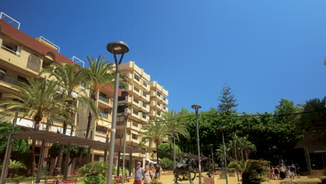 a low-angle view of tall palm trees and modern buildings under a bright blue sky, capturing the essence of a sunny day in a coastal city