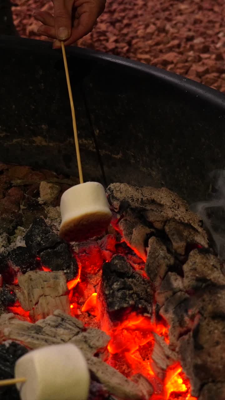 Arrostire marshmallow su un caldo falò di notte