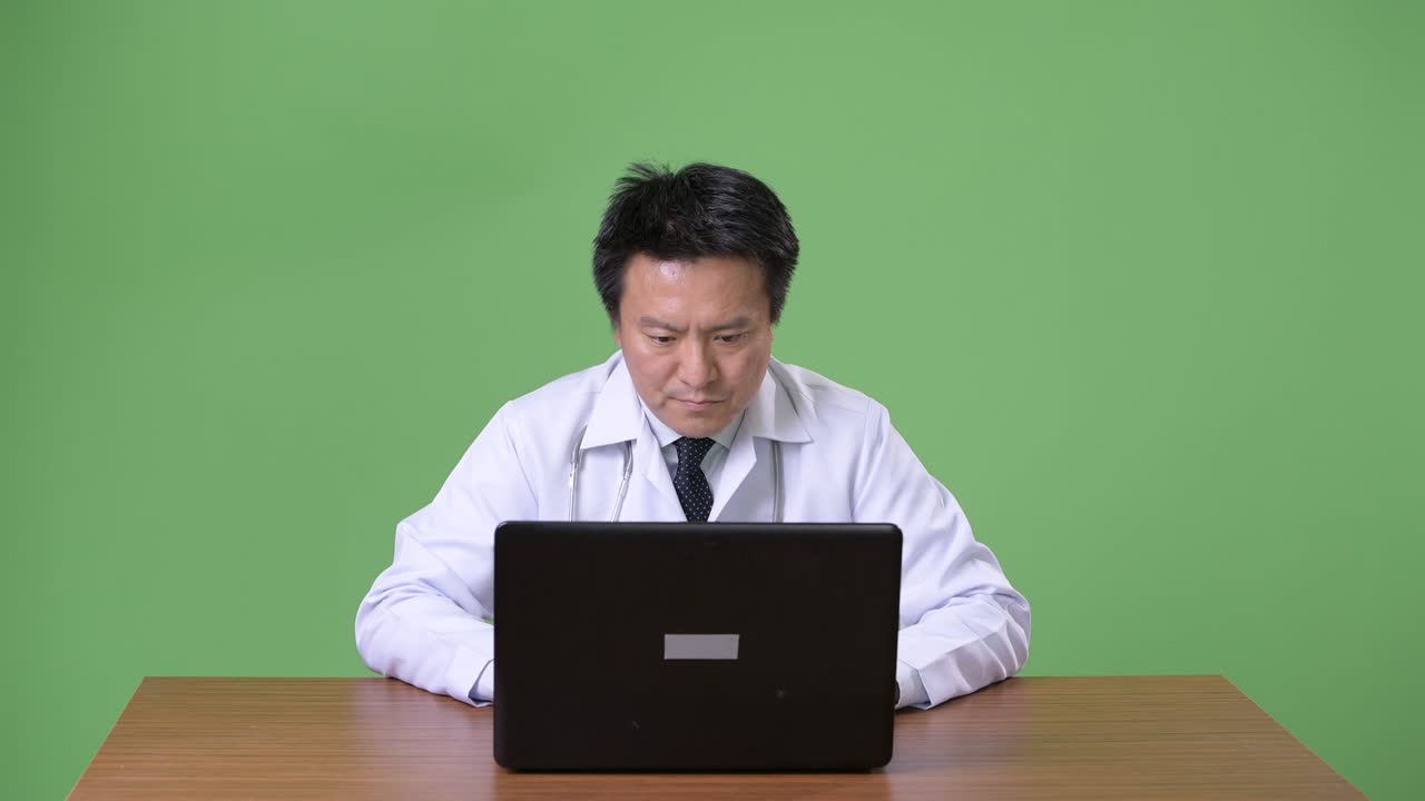 성숙한 일본인 남성, 초록색 배경의 의사