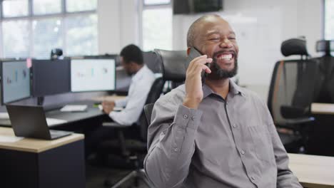 Fröhliche-Afroamerikanische-Geschäftsleute,-Die-Im-Büro-Auf-Dem-Smartphone-Sprechen-Und-Den-Computer-Nutzen,-Zeitlupe