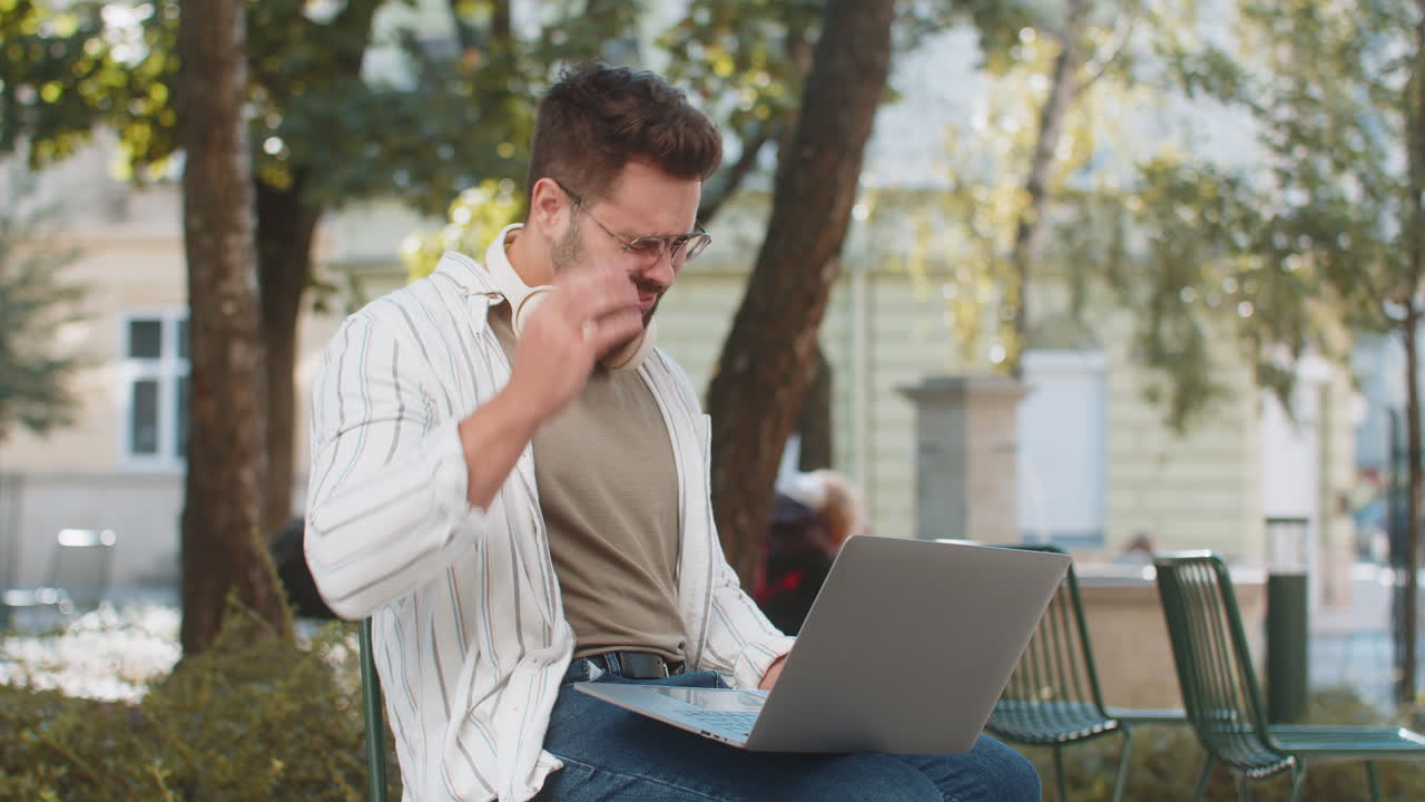 joven caucásico usando portátil navegación pierde resultados de la lotería malas noticias sentado en la calle de la ciudad