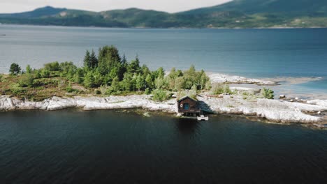 a solitary sod roof house standing on the shore of an island in the middle of a fjord