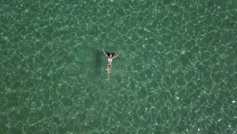 Mujer-En-Bikini-Se-Desliza-Sobre-Su-Espalda-A-Través-De-Las-Verdes-Aguas-Del-Mar-Egeo