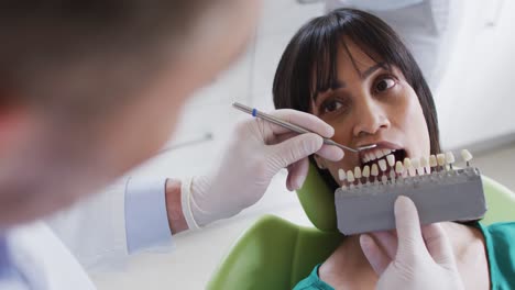 caucasian male dentist examining teeth of female patient at modern dental clinic