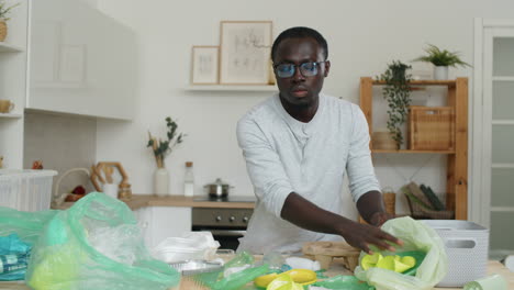 african american man sorting plastics in kitchen