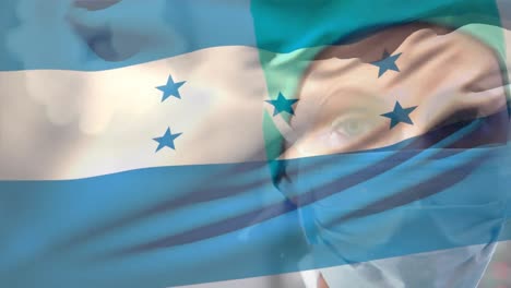 Animation-of-waving-honduras-flag-against-portrait-of-caucasian-female-surgeon-at-hospital