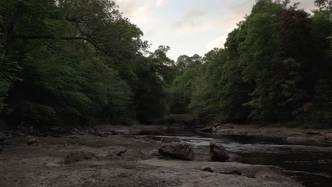 Río-Suave-Que-Corre-A-Través-De-Rocas-Y-árboles-A-La-Luz-De-La-Tarde