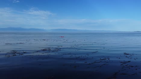 Kayaker-with-red-kayak-on-Pacific-ocean-water-in-West-Coast-Canada