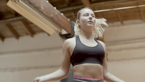 medium shot of focused woman jumping rope in gym