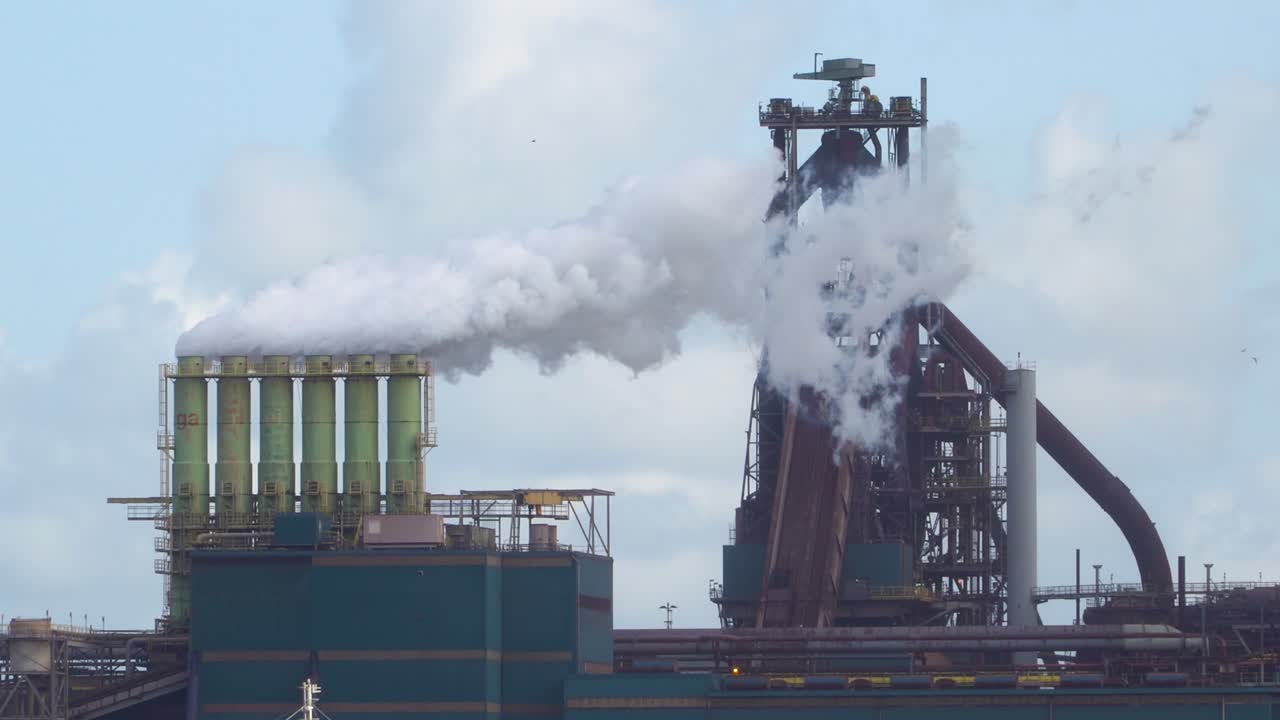 공장이 배경에서 작동하는 클로즈업에서 파이프와 증기로 네덜란드의 철강 공장에 의한 오염