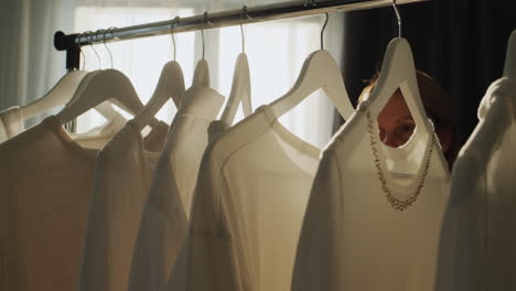 a woman chooses clothes in the dressing room. silhouette in the sun, side view