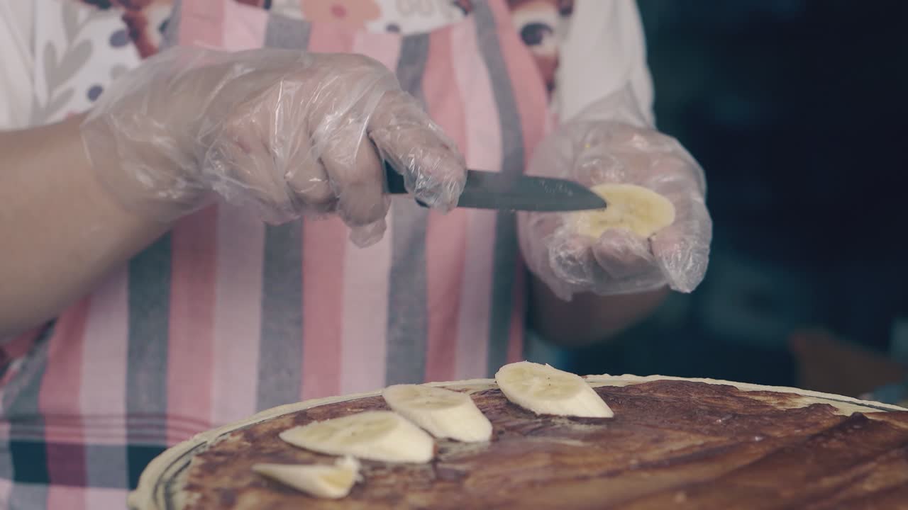 el chef pone rebanadas de plátano en panqueque con chocolate en la cafetería