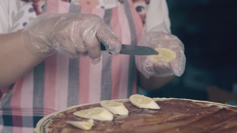 chef puts banana slices on pancake with chocolate in cafe